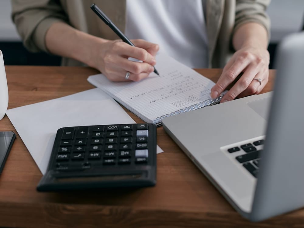 Working through a personal tax return with notes, a calculator, and a laptop